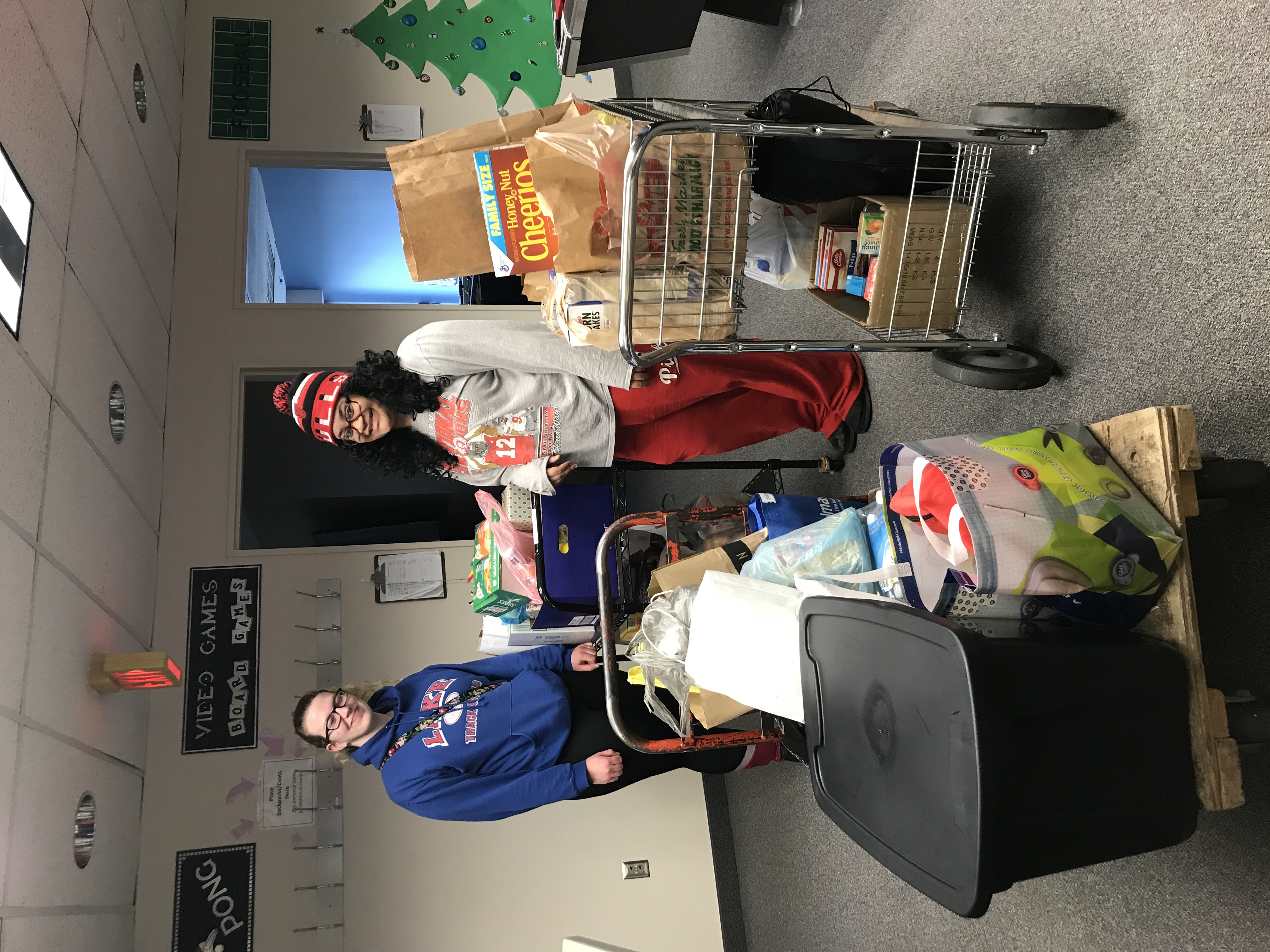 two Phi Theta Kappans posing with carts of pantry items.